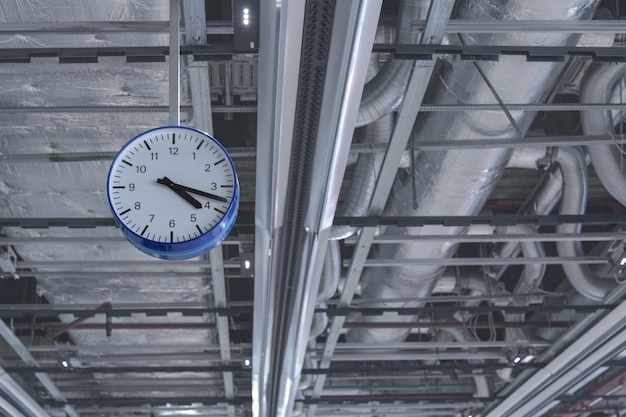 Vista del reloj que cuelga del techo contra los tubos de ventilación.