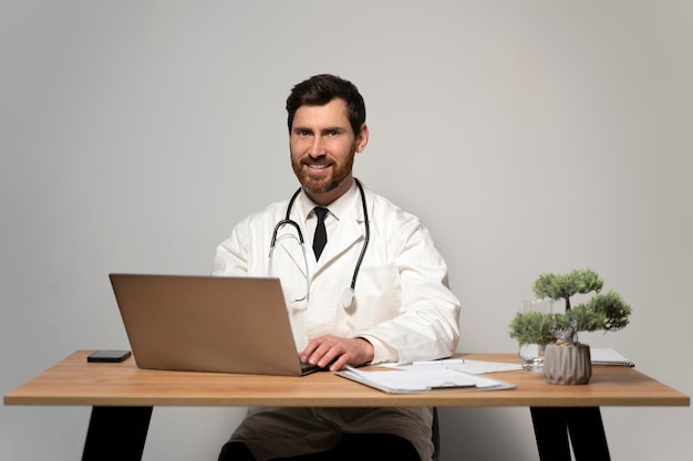 Vista de retrato en la cintura del doctor feliz sonriendo a la cámara mientras posa en su lugar de trabajo