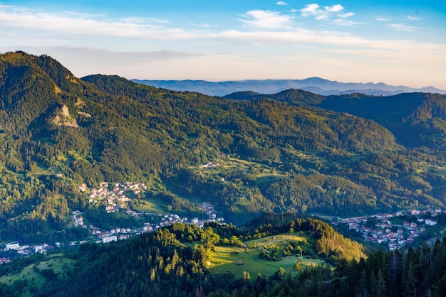 Vista desde la roca a la ciudad de Smolyan con prados para pasear ganado y casas entre la cordillera de las montañas Ródope