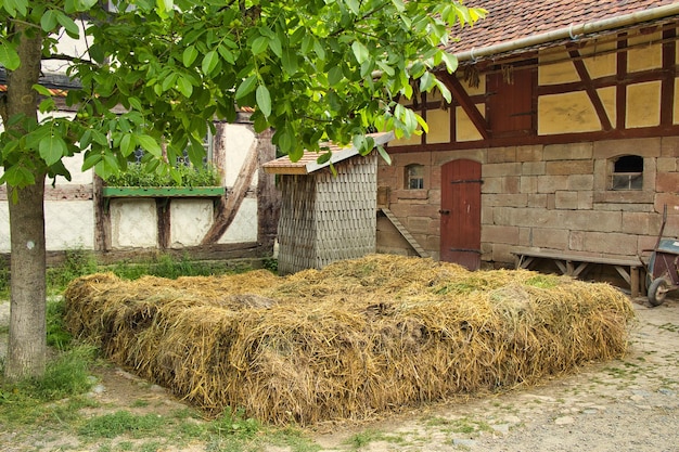 Vista rural de una granja de pueblo con baño al aire libre y hey en el patio