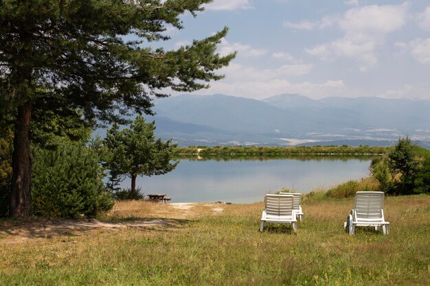 Vista de las sillas de sol en la orilla del lago entre el bosque y las montañas en Bulgaria en un su