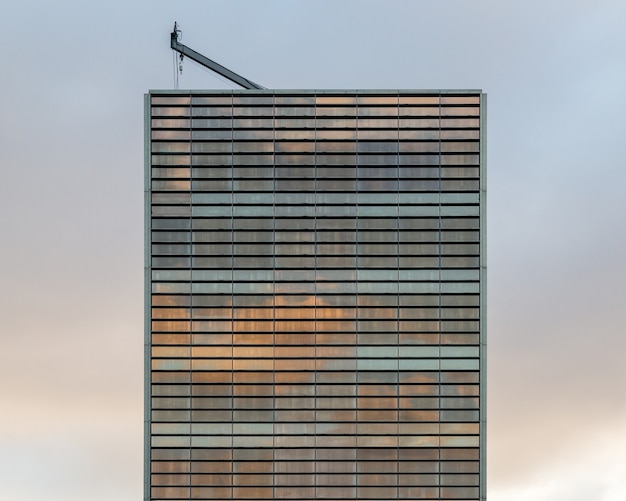 Una vista simple de un edificio de cristal con una grúa en la parte superior al atardecer