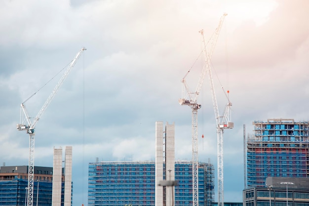 Vista sobre grúas torre y sitios de construcción de edificios alrededor del paisaje de la ciudad La ciudad está subiendo el concepto