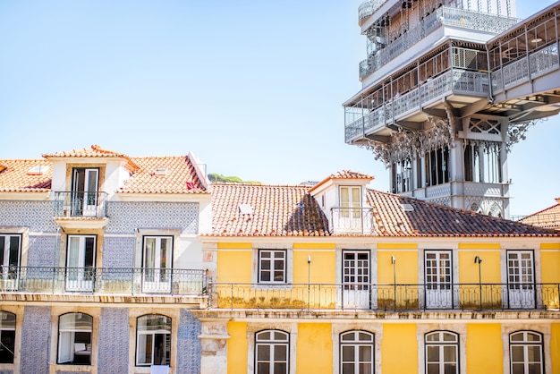 Foto vista sobre os edifícios antigos com o famoso elevador de metal santa justa durante o tempo ensolarado na cidade de lisboa, portugal