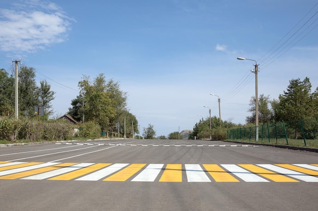 Una vista sobre una superficie amarilla y blanca enyesada en un paso de cebra en una carretera en una zona rural