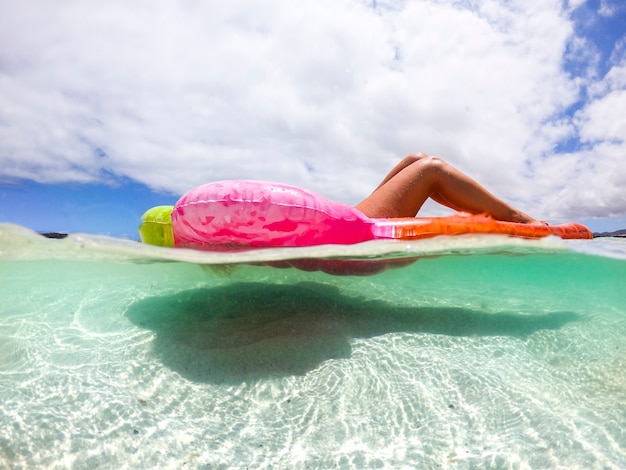 Vista submarina de una bonita mujer caucásica disfrutando de las vacaciones de verano relajándose en un lilo de moda de color en el mar transparente del Caribe - gente tomando el sol en la playa tropical