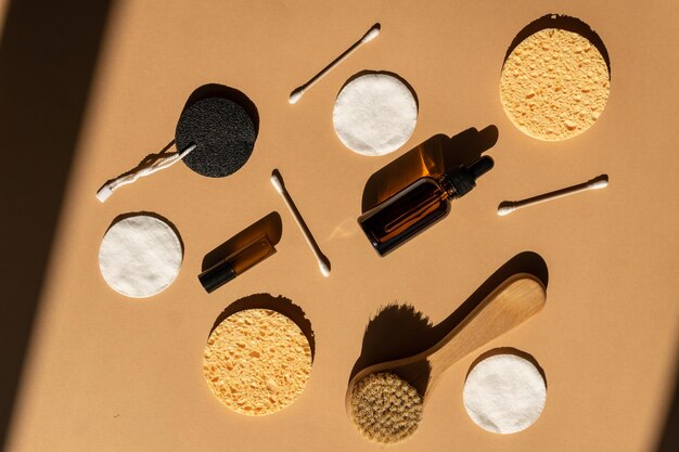 Foto vista superior de accesorios y cosméticos de masaje seco concepto de cosméticos ecológicos de cero residuos cepillo natural de madera para la cara almohadillas de algodón palillos para los oídos y aceites esenciales de belleza en botellas de vidrio oscuro