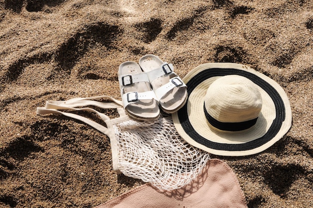 Vista superior accesorios de playa bolsa de compras de malla ecológica sandalias de sombrero de paja