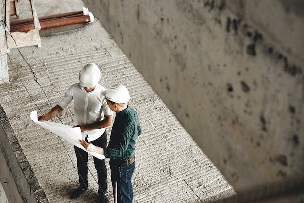 Vista superior de un adulto arhitecht y su trabajador hablando de la construcción en construcción en el lugar de trabajo.