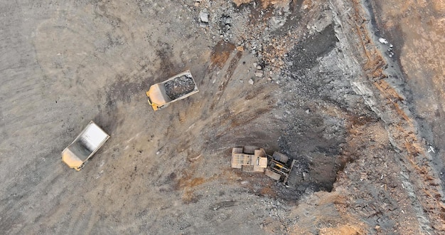 Vista superior aérea en excavadora carga grava de piedra en un camión en una cantera de piedra triturada