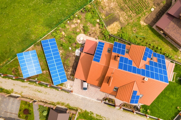 Vista superior aérea de la nueva casa residencial moderna casa de campo con azul brillante sistema de paneles fotovoltaicos fotovoltaicos en el techo. Concepto de producción de energía verde ecológica renovable.