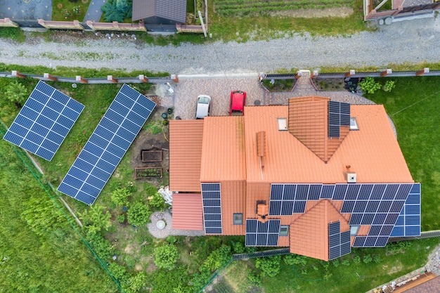 Vista superior aérea de la nueva casa residencial moderna casa de campo con azul brillante sistema de paneles fotovoltaicos fotovoltaicos en el techo. concepto de producción de energía verde ecológica renovable.