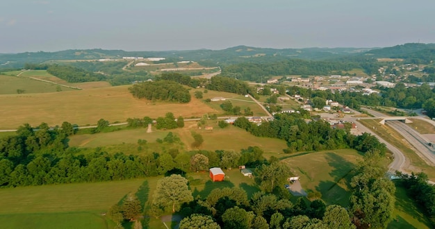 Vista superior aérea de Pensilvania, EE.UU., de un pequeño pueblo rodeado de árboles y colinas cerca de la autopista