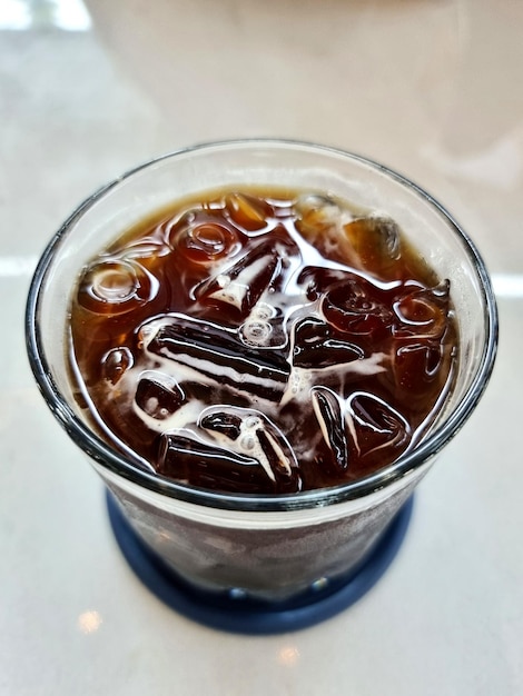 Vista superior del agua de cola con hielo en un vaso sobre un fondo blanco