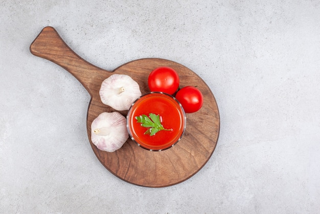 Vista superior de ajo y tomate con salsa sobre tabla de cortar de madera.