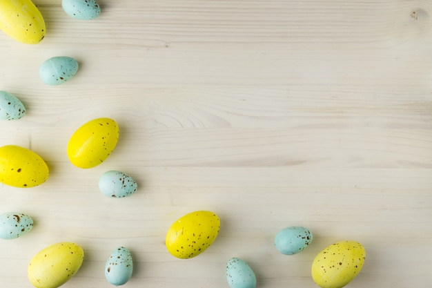 Vista superior de un amarillo y azul huevos de Pascua sobre fondo de madera clara con espacio para mensajes.