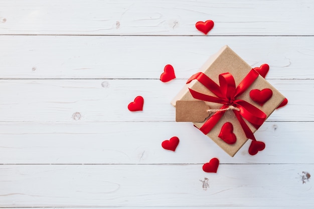 Vista superior (arriba) caja de regalo y la cinta roja y el corazón rojo de San Valentín en mesa de madera. Fondo de San Valentín.
