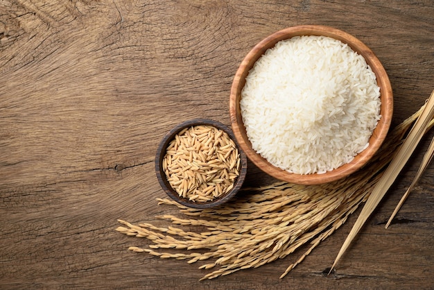 Vista superior del arroz jazmín blanco con espigas de arroz con cáscara sobre fondo de madera