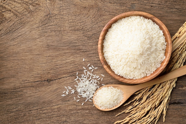 Vista superior del arroz jazmín blanco con espigas de arroz con cáscara sobre fondo de madera