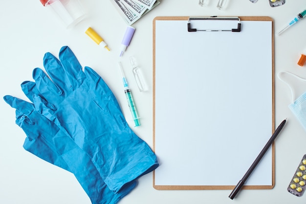 Vista superior de artículos médicos y hoja en blanco de papel vacía sobre el fondo blanco. Concepto de salud y medicina