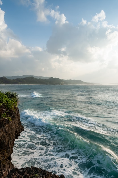 Vista superior de un áspero mar verde esmeralda olas rocas costeras y montañas en el fondo