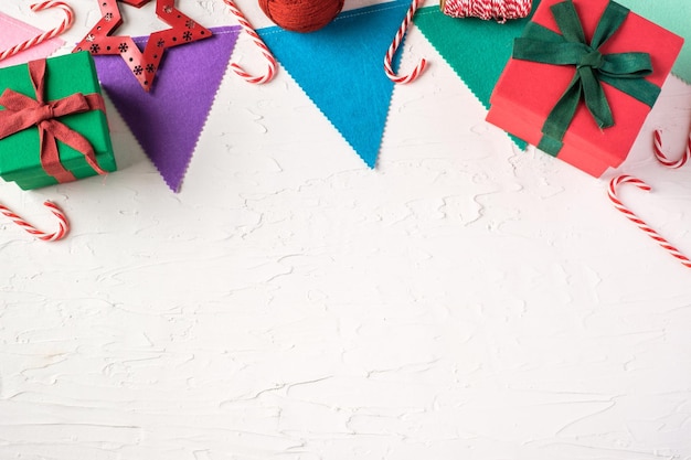 Vista superior de la bandera de fiesta colorida de navidad y caja de regalo en la mesa de hormigón de pasta blanca