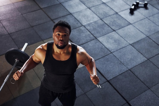 Vista superior Barbell en el suelo Un hombre afroamericano fuerte con ropa deportiva tiene un día de entrenamiento en el gimnasio