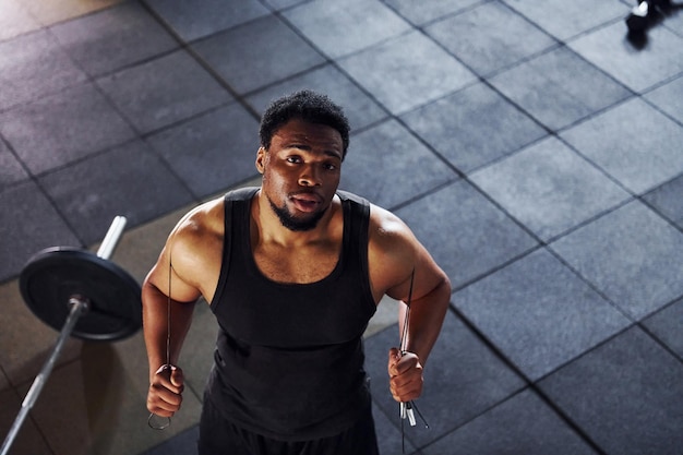 Vista superior Barbell en el suelo Un hombre afroamericano fuerte con ropa deportiva tiene un día de entrenamiento en el gimnasio