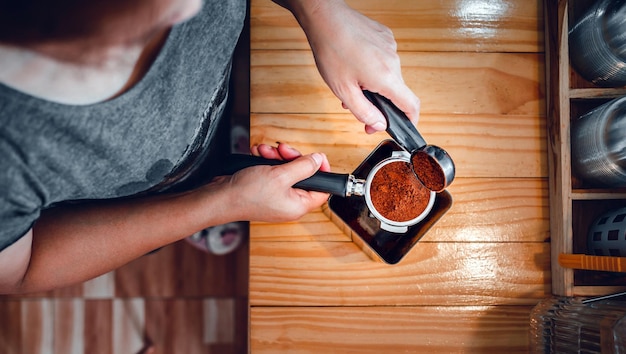 Vista superior del barista de mano vierte café molido en polvo tostador de granos de café que se vierte en un portafiltro