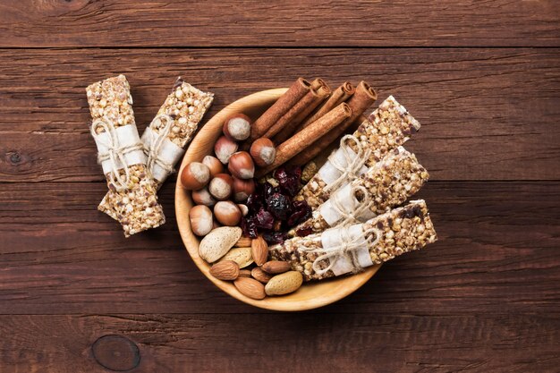 Vista superior de barras de cereales con diferentes frutos secos y muesli e ingredientes tazón