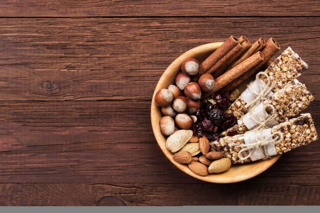 Vista superior de barras de cereales con diferentes frutos secos y muesli e ingredientes tazón