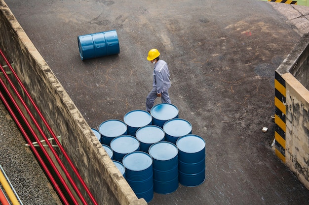 La vista superior de los barriles de petróleo se mueve verticalmente para que el trabajador masculino ayude a organizar.