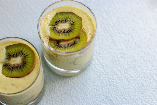 vista superior del batido de kiwi en un vaso sobre fondo azul con espacio de copia