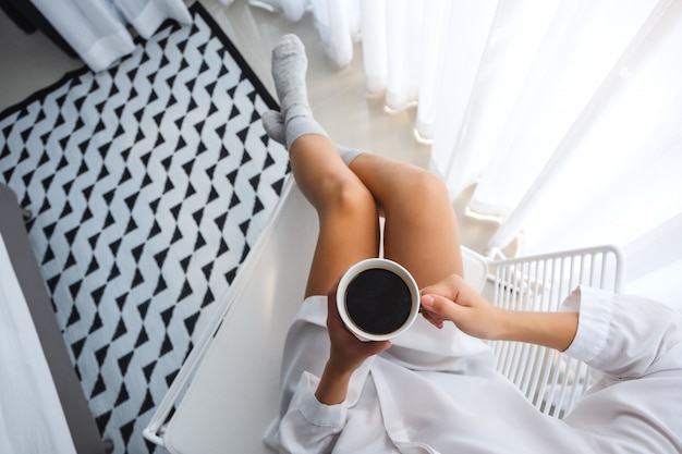 Vista superior de una bella mujer bebiendo café caliente en el dormitorio en casa por la mañana