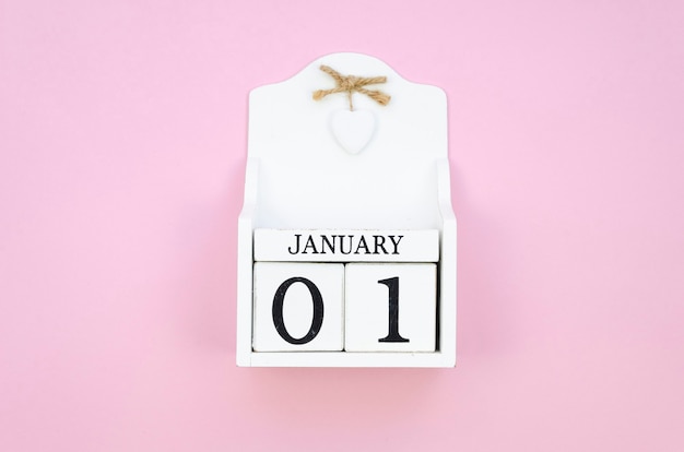 Vista superior blanco calendario de cubo de madera del 1 de enero sobre un fondo rosa.