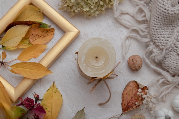 Vista superior del bodegón de la vendimia del otoño con las hojas caídas, la rosa seca, las velas y la manta tejida. Concepto de ambiente otoñal