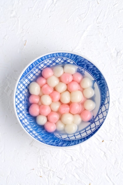 Vista superior de bolas de bola de masa de arroz glutinoso tangyuan tang yuan rojo y blanco en un tazón azul