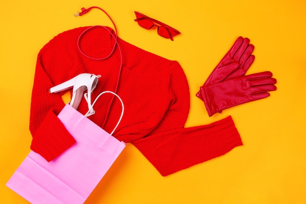 Foto vista superior de la bolsa rosa con suéter rojo, zapatos elegantes, cinturón rojo y guantes y gafas rojas