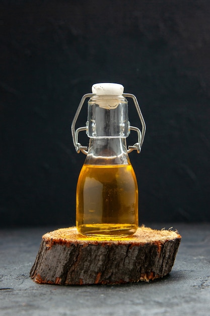 Vista superior de la botella de aceite en una tabla de cortar de madera marrón sobre fondo de onda oscura con espacio libre