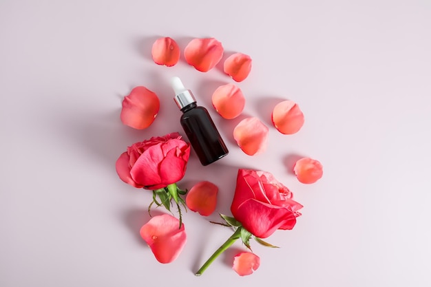 Vista superior de una botella cosmética con suero de aceite de rosa o un producto de autocuidado natural nutritivo un fondo de pétalos de rosa