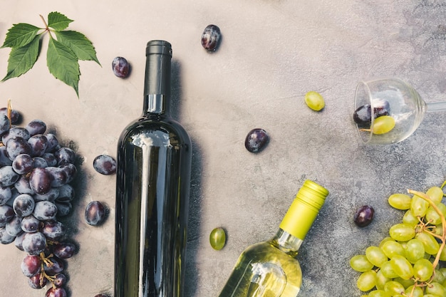 Vista superior de la botella de vino tinto y blanco copa de vino de vid verde y uva madura en la mesa de piedra oscura de la vendimia ...