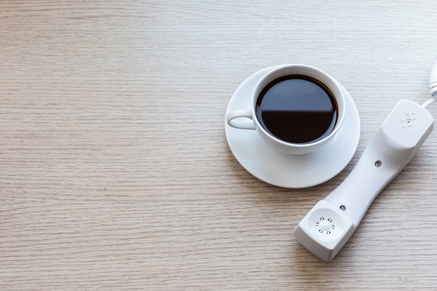 Vista superior branca xícara de café e escritório telefone na mesa de madeira