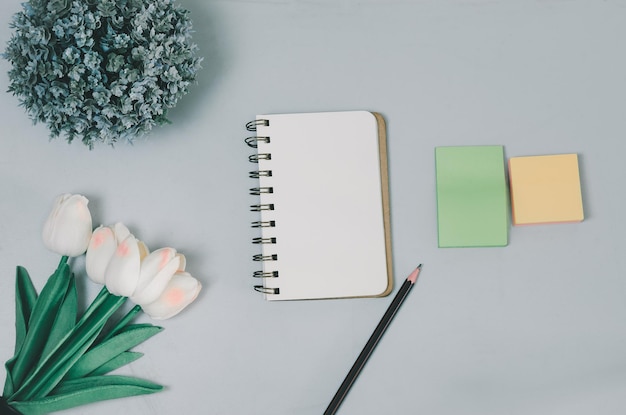 Foto vista superior caderno em branco flor e lápis na mesa plana com espaço de cópia da mesa de escritório