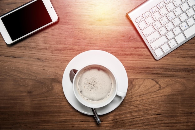 Foto vista superior café quente na mesa de escritório de madeira com teclado de computador