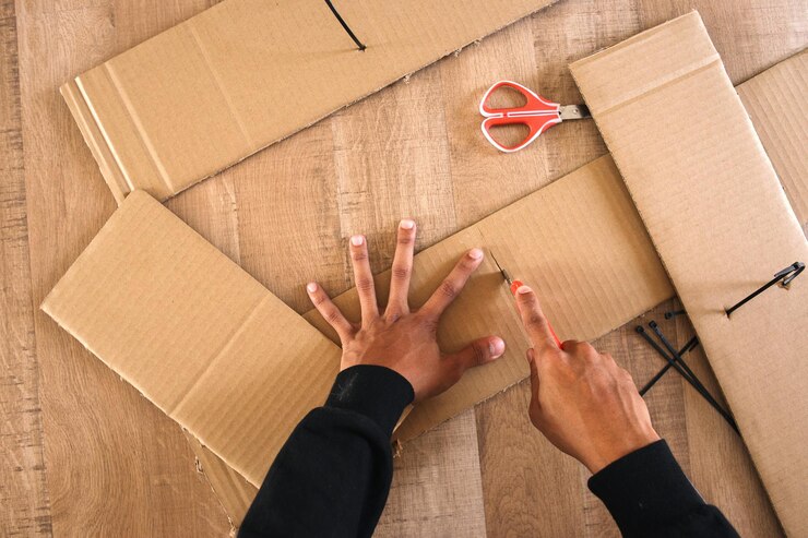 Foto vista superior de la caja de cartón cortada a mano masculina con cortador
