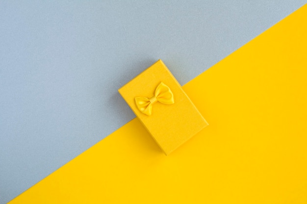 Vista superior de la caja de regalo amarilla en la superficie de dos tonos