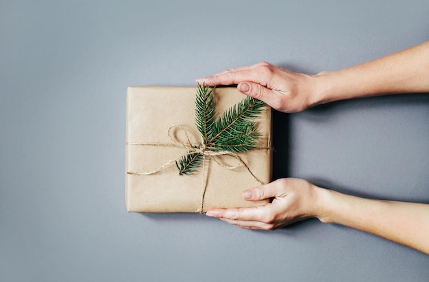 Vista superior de una caja de regalo embalada en papel artesanal en manos femeninas