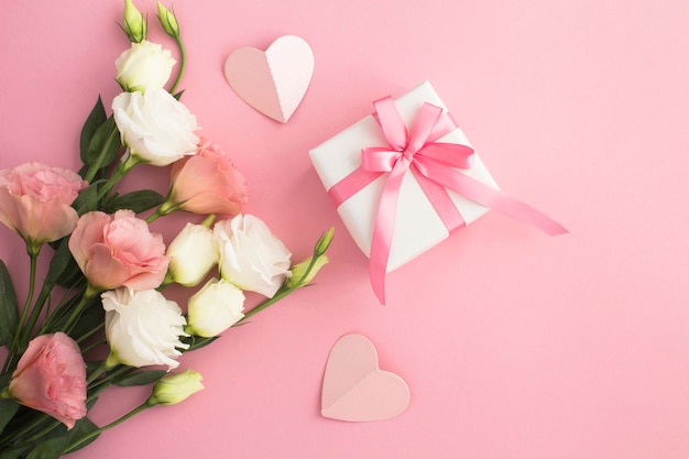 Vista superior de la caja de regalo de flores blancas y rosas sobre fondo rosa