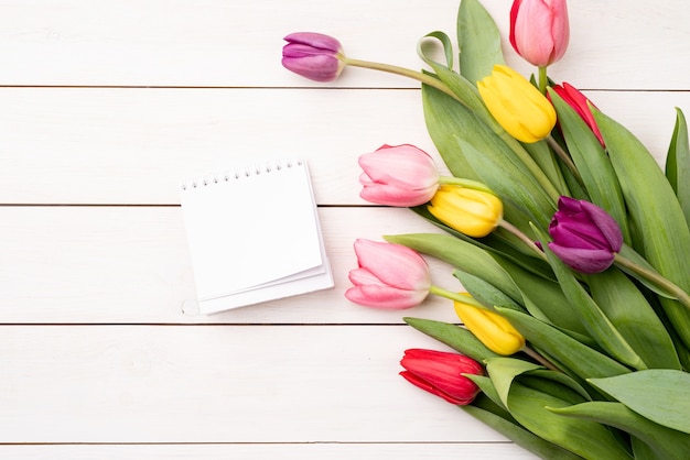 Vista superior del calendario en blanco con tulipanes de colores sobre fondo blanco.