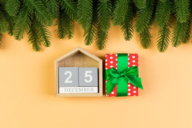 Vista superior del calendario de madera, caja de regalo y abeto sobre fondo de colores. El veinticinco de diciembre. Tiempo de Navidad con espacio de copia.